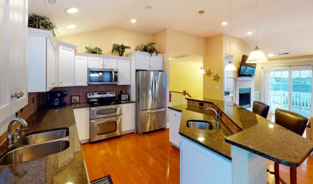 The Absolut Paradise custom kitchen featuring white cabinetry, dark granite countertops, and contemporary design