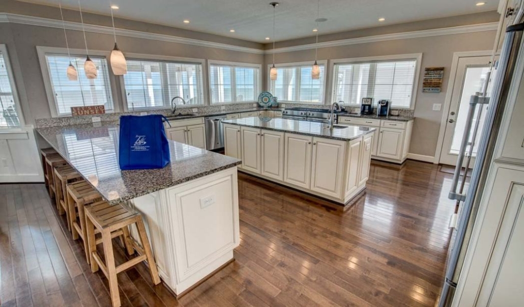 The Aquatic Dreams custom kitchen with white cabinetry, granite countertop, and large windows that add natural light