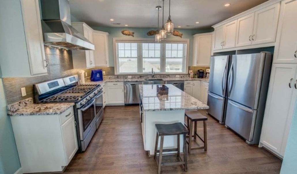 Kitchen area in project At Last with enough space, elegant white cabinetry and large windows for natural light