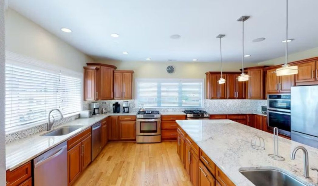 The Atlantic Villa Fran-to-Sea custom kitchen with wooden cabinetry, granite countertop, and aesthetic modern design