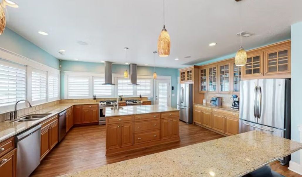 The elegant custom kitchen of Bellissimo featuring wooden cabinets, large windows and counter top granite