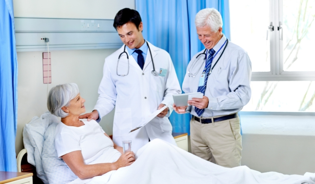 A two doctors talking to the patient in a hospital bed, showcasing healthcare teamwork in Virginia Beach, VA.