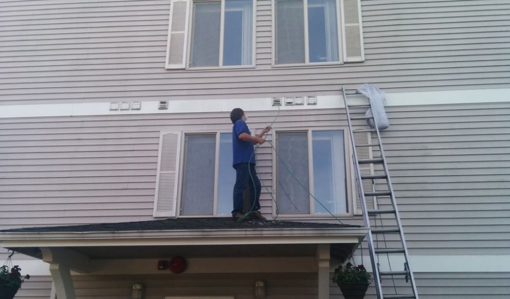 A man is cleaning windows , underscoring the significance of seasonal home maintenance for safety and upkeep.