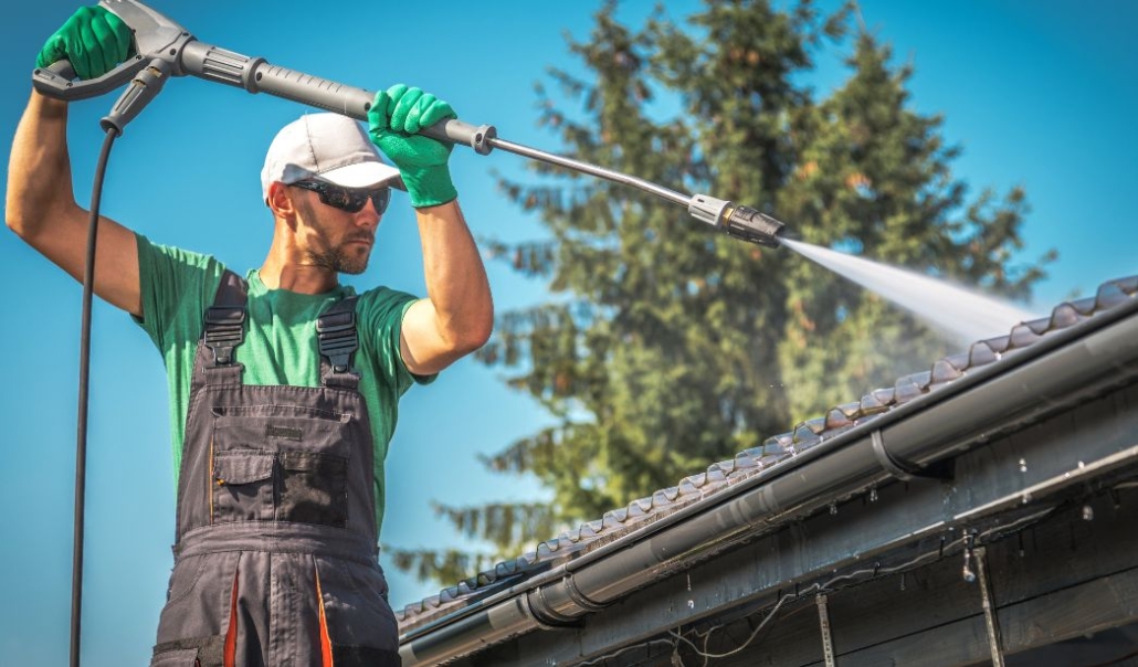 A man is cleaning the roof to ensure that the gutters are properly maintained for seasonal safety at home.