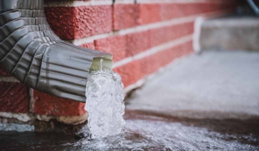 Water emerging from a pipe, highlighting the significance of gutter and downspout maintenance for seasonal home upkeep.