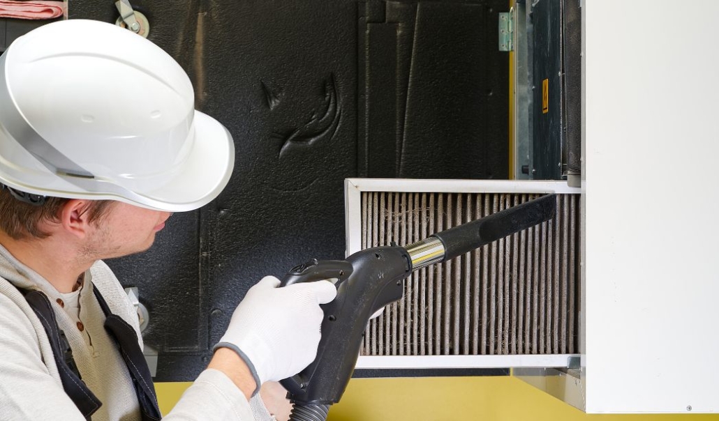 A man replacing HVAC air filters  in a room, ensuring optimal air quality for seasonal home maintenance.