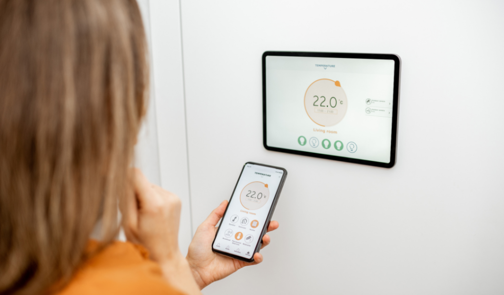 A person setting a digital thermostat, emphasizing seasonal home maintenance for a secure and comfortable living environment.