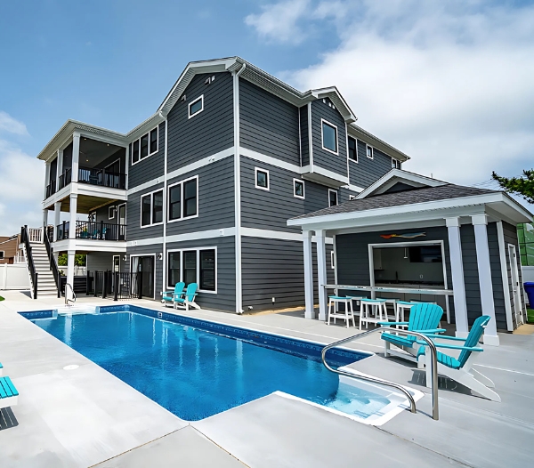 A beautiful house featuring a pool and deck chairs, showcasing Courthouse Estates by Virginia Beach Home Builders.