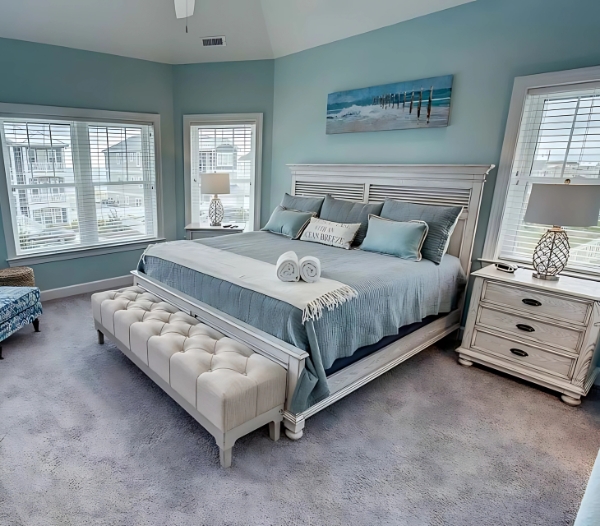 A cozy bedroom featuring blue walls and a neatly made bed, showcasing expert craftsmanship by Little Neck Virginia Beach Home Builders.