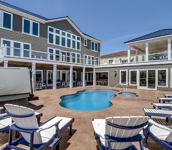 A spacious house featuring a pool and deck chairs, showcasing local expertise from Little Neck Virginia Beach Home Builders.