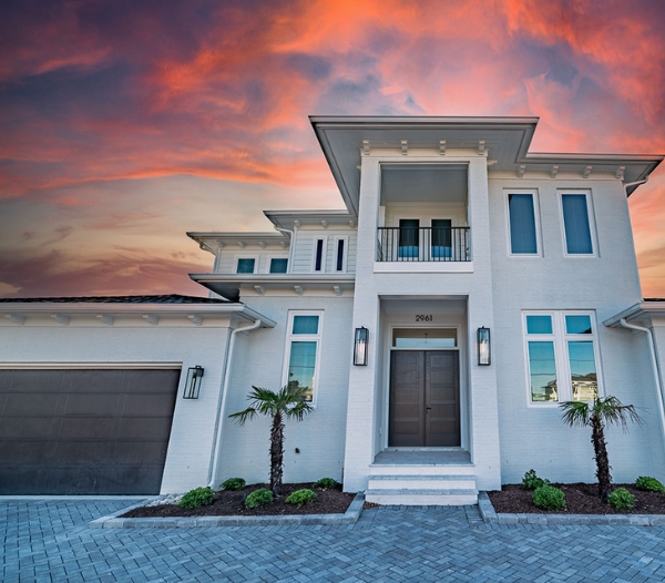 A stunning white home against a vibrant sunset, showcasing the beauty of Virginia Beach living and enhancing property value.