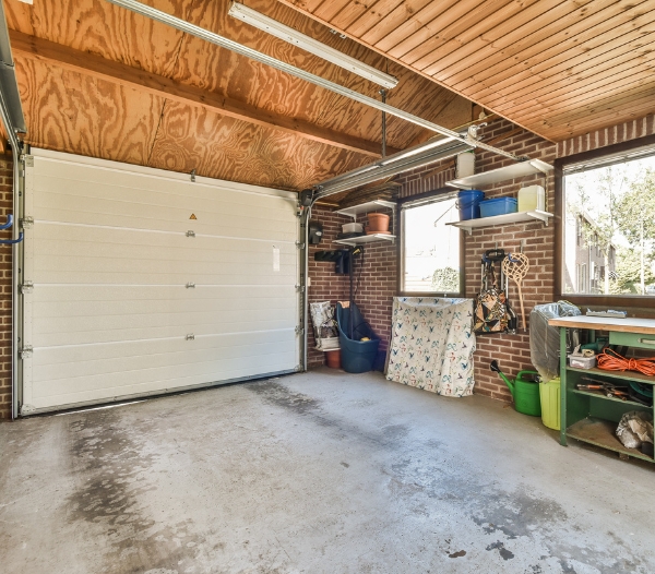 A spacious garage with an open door showcasing a well-organized workbench, ideal for optimizing storage space.