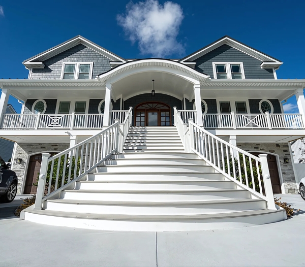 A spacious white house featuring stairs to the front door, representing home improvement and increased value in Virginia Beach.