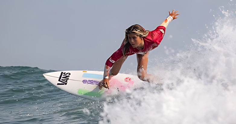 A woman in a red shirt skillfully rides a surfboard, showcasing outdoor recreation in Virginia Beach.