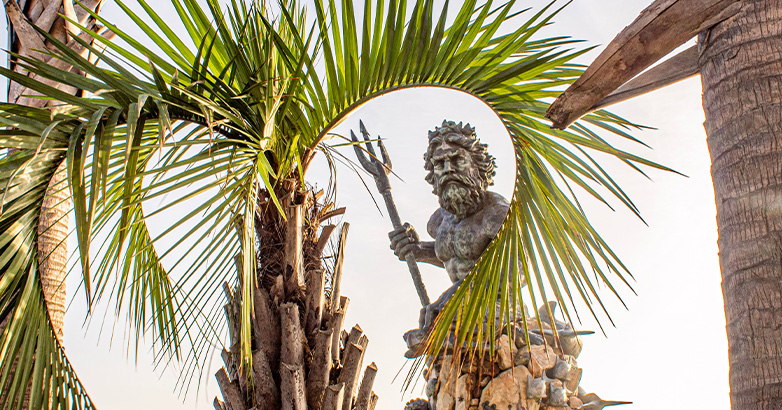 A statue of King Neptune framed by palm trees showcases Virginia Beach's fun and family-friendly attractions.