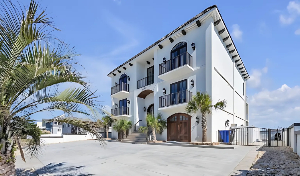 A charming white house with palm trees and a driveway, highlighting the work of Castleton Virginia Beach Home Builders.