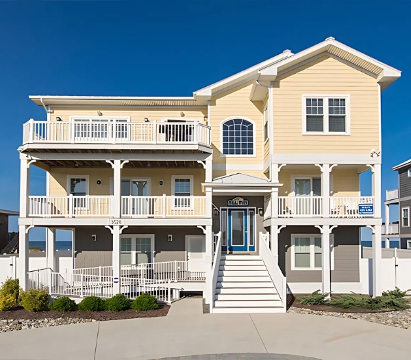 A large beach house with an expansive deck and stairs, exemplifying timely project completion by Castleton Virginia Beach Home Builders.