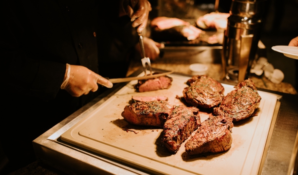 A chef is seen preparing steak on a cutting board, representing the diverse dining options in Virginia Beach.
