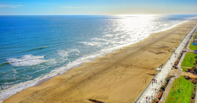 Aerial view of Virginia Beach showcasing the sandy shore and ocean waves, highlighting outdoor activities and beach life.