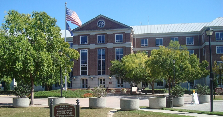 A large building surrounded by trees, featuring a flag, representing family-friendly communities in Virginia Beach.