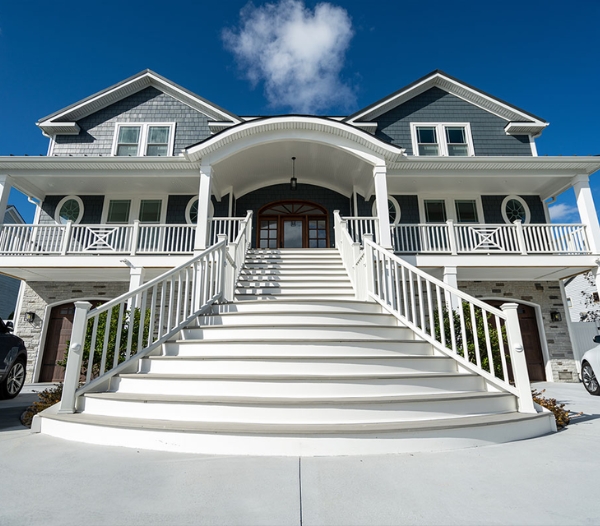 A prominent white house with a large staircase, showcasing the trusted reputation of Indian River Virginia Beach Homebuilders.