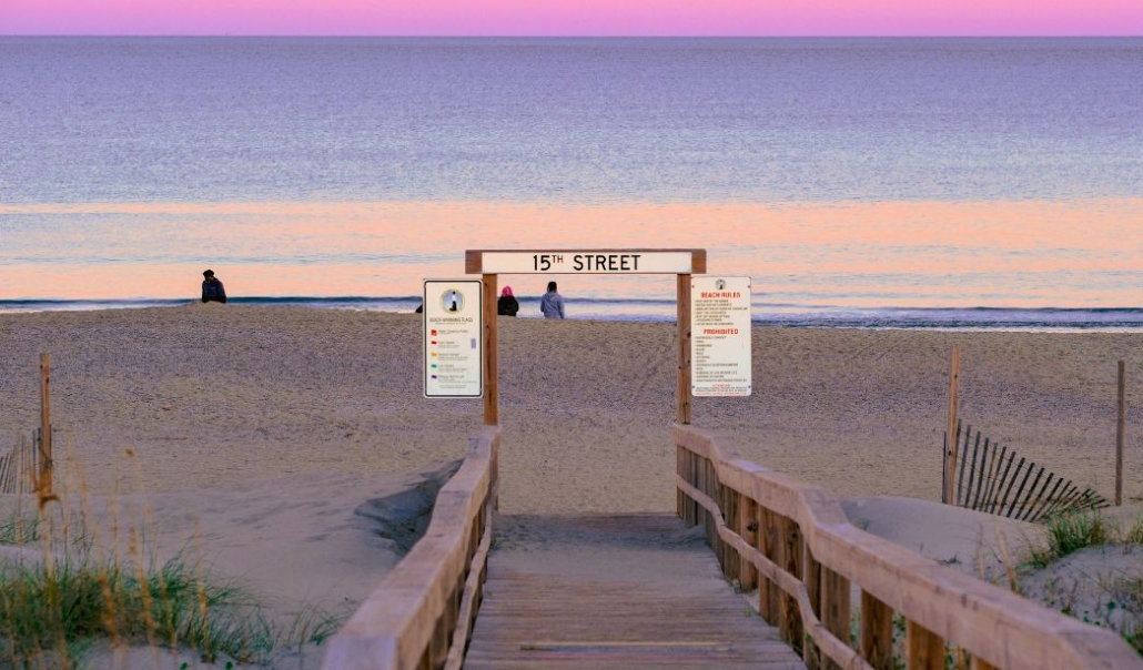 A wooden walkway leads to Virginia Beach, marked by a sign indicating the beach's entrance.