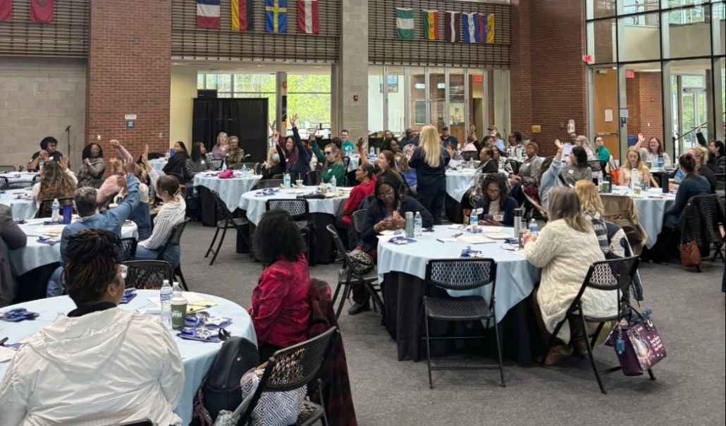 Numerous individuals gathered at tables in a large room, participating in a session on retirement and education opportunities.