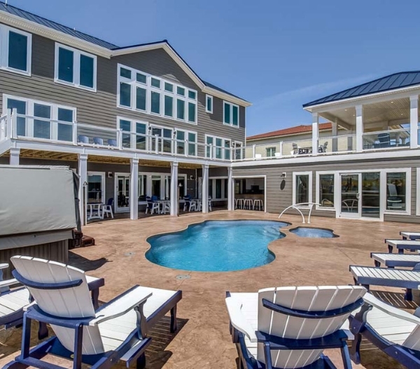 A residential property with a pool and deck chairs, highlighting the craftsmanship of Nimmo Virginia Beach Homebuilders.