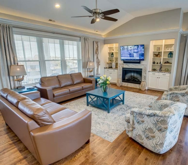 Modern living room with leather seating and a flat-screen TV, highlighting the craftsmanship of Strawbridge Virginia Beach Homebuilders.