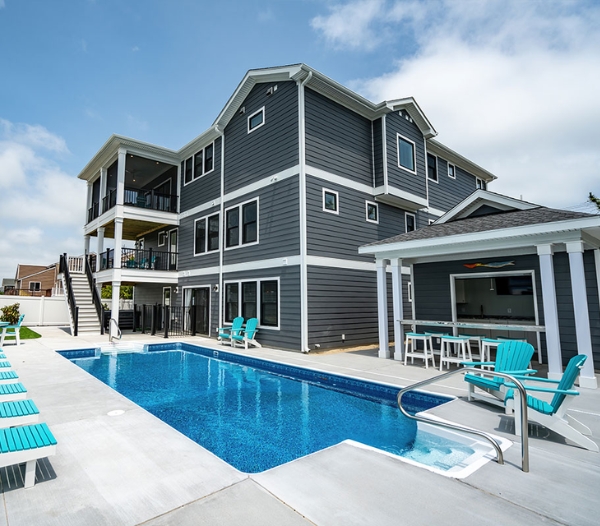 Spacious home with a pool and patio furniture, highlighting the work of Strawbridge Virginia Beach Homebuilders.