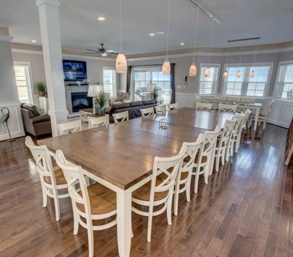 A spacious dining room featuring hardwood floors and elegant white chairs, showcasing superior craftsmanship by Strawbridge Homebuilders.