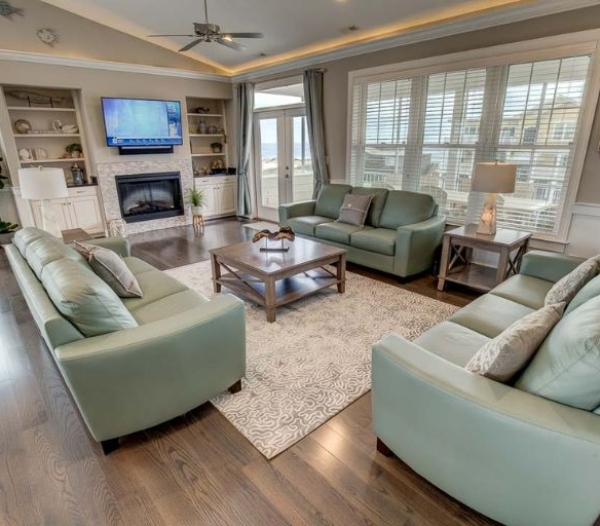 A modern living room with a couch, chair, and television, representing the quality of Heron Ridge Virginia Beach Homebuilders.
