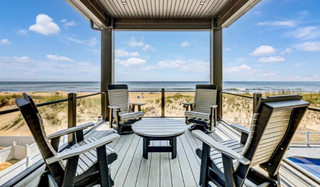 A deck with seating and a table provides an ocean view, emphasizing the advantages of adding a deck to your home.