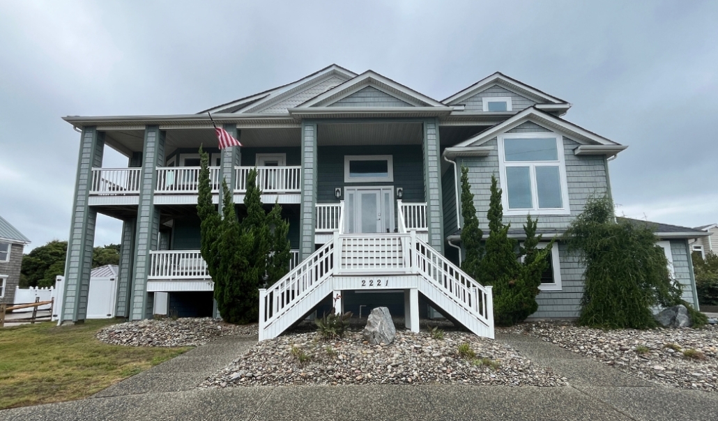A house featuring stairs leading to a front porch, highlighting a steel door replacement for enhanced entry appeal.