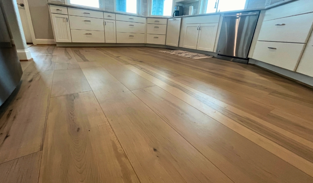 A modern kitchen featuring hardwood floors and white cabinets, showcasing a stylish home remodel that enhances value.