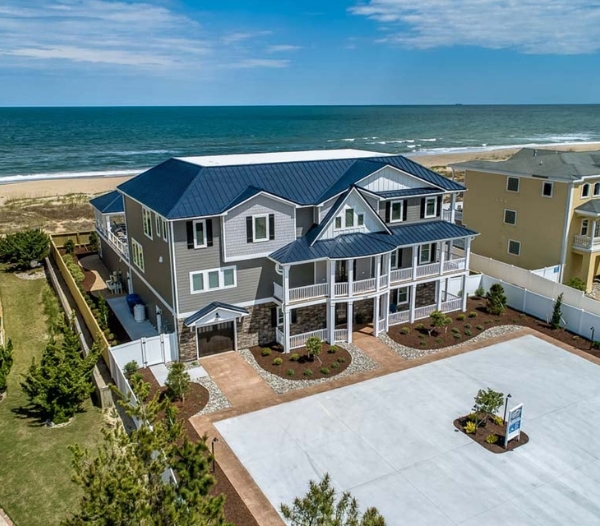 A beach house with a blue roof and large driveway, showcasing Ocean Lakes Virginia Beach Homebuilders' project management.