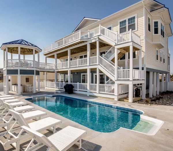 A large white house with a pool and deck, showcasing custom coastal designs by Ocean Lakes Virginia Beach Homebuilders.