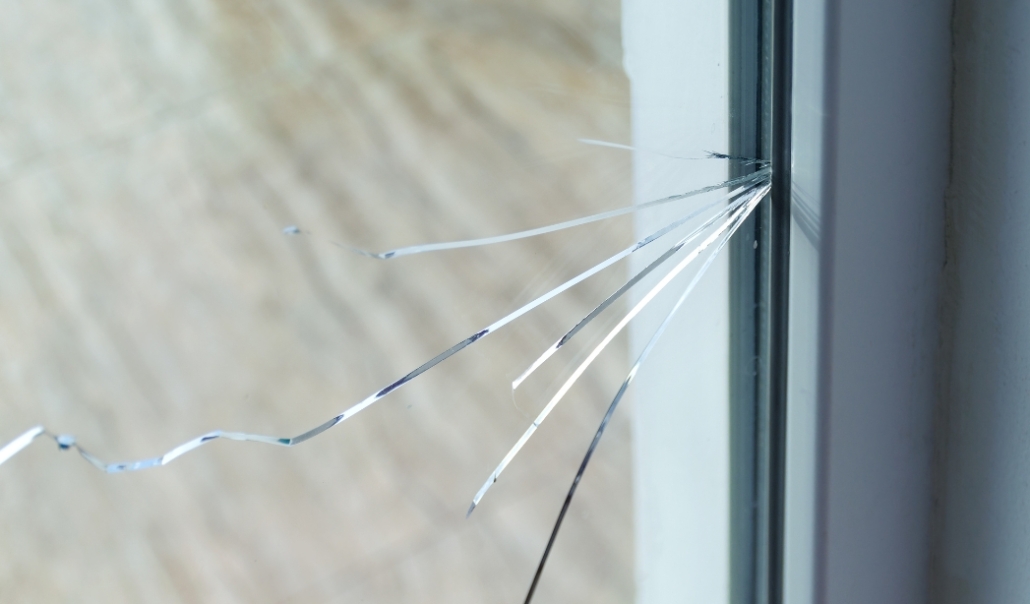 A broken window with shattered glass, illustrating the need for replacement due to visible damage and cracks.