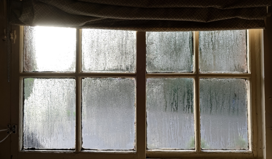 A frosty window covered by a blind, highlighting the problem of foggy panes and the importance of timely window replacement.