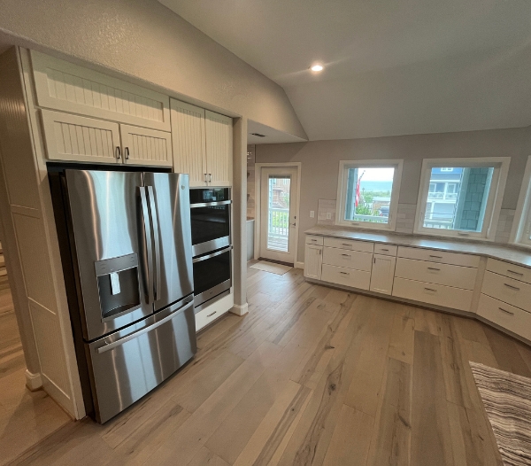 A modern kitchen featuring stainless steel appliances and elegant wood floors, showcasing tailored luxury design in Virginia Beach.
