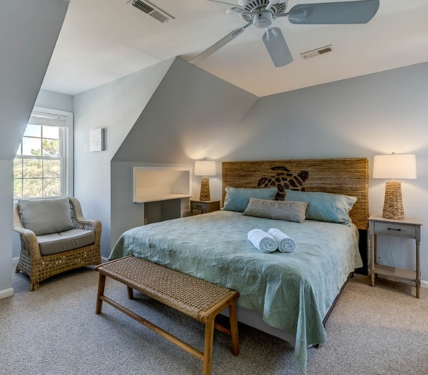 A cozy bedroom featuring a bed, a chair, and a ceiling fan, showcasing a comfortable living space.