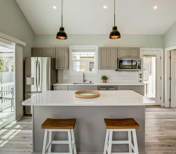 A modern kitchen featuring a center island with two stools, showcasing quality craftsmanship by a Virginia Beach contractor.