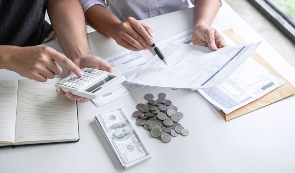 A couple, calculating expenses with a notebook, calculator, and money, 