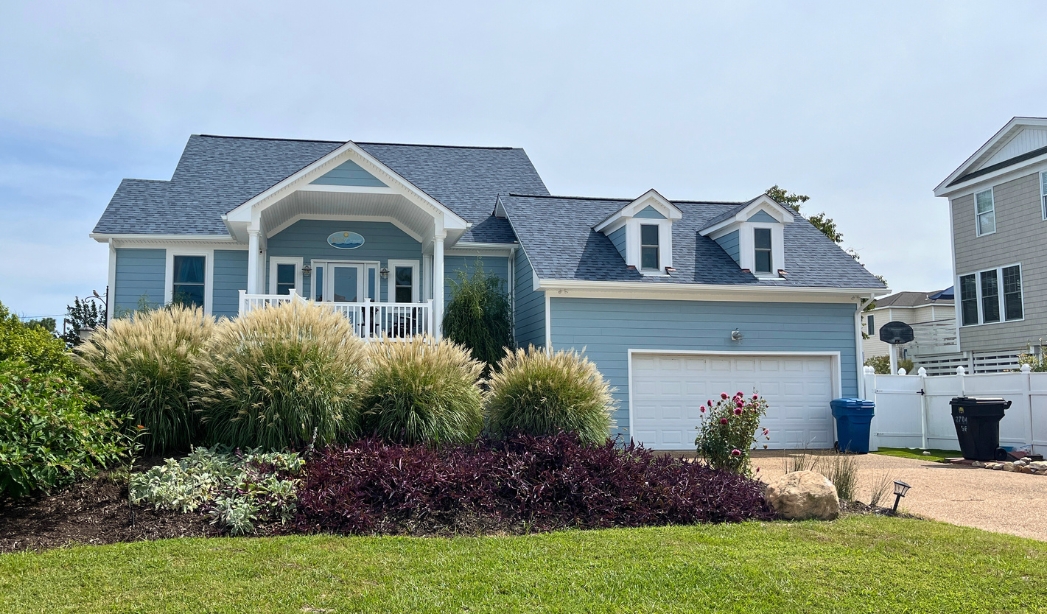 A blue house surrounded by a spacious yard and well-maintained landscaping in Virginia Beach.