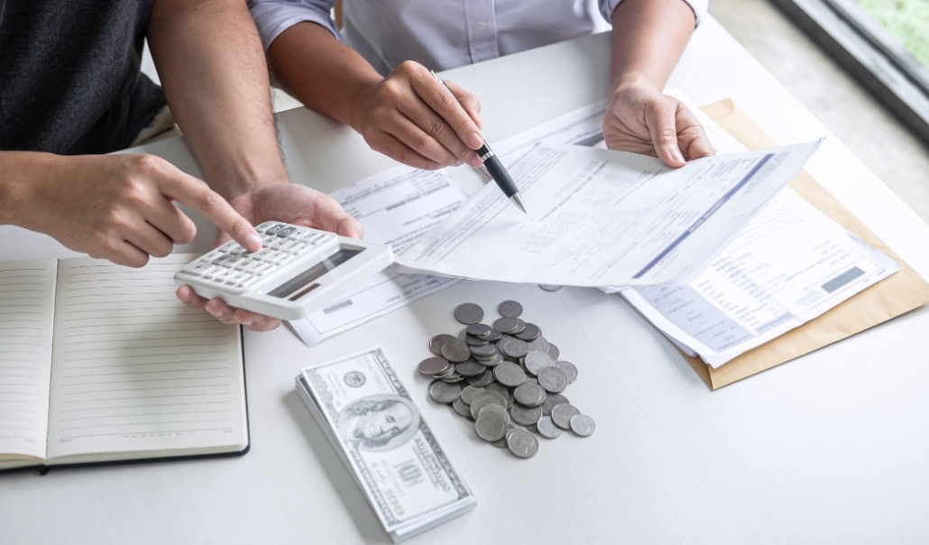 A businessman and woman engaged in financial calculations at a desk, discussing budgeting for custom home design.