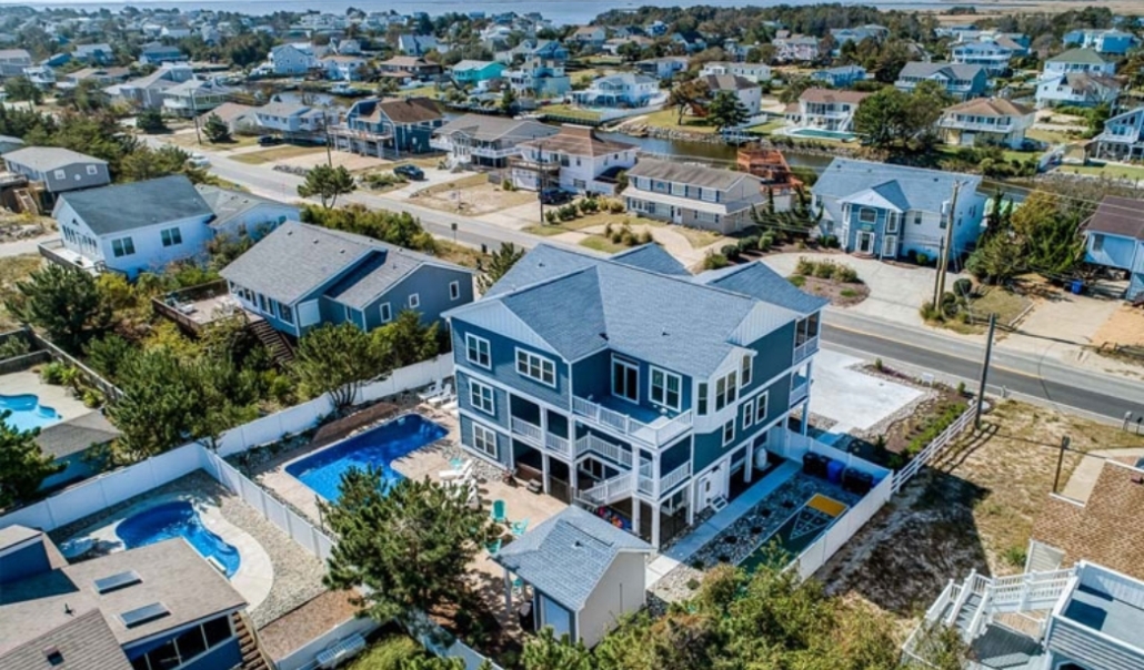 Aerial view of a beach house featuring a pool, illustrating site evaluation for custom home design.