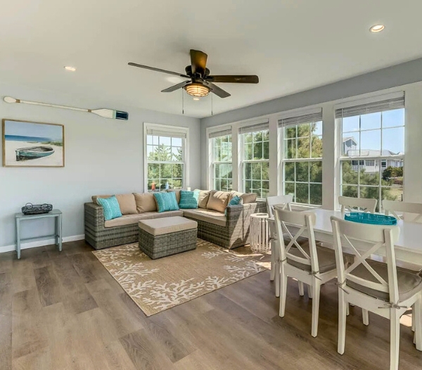 A modern living room with a ceiling fan and a table, representing customized design plans for remodeling services in Virginia Beach.