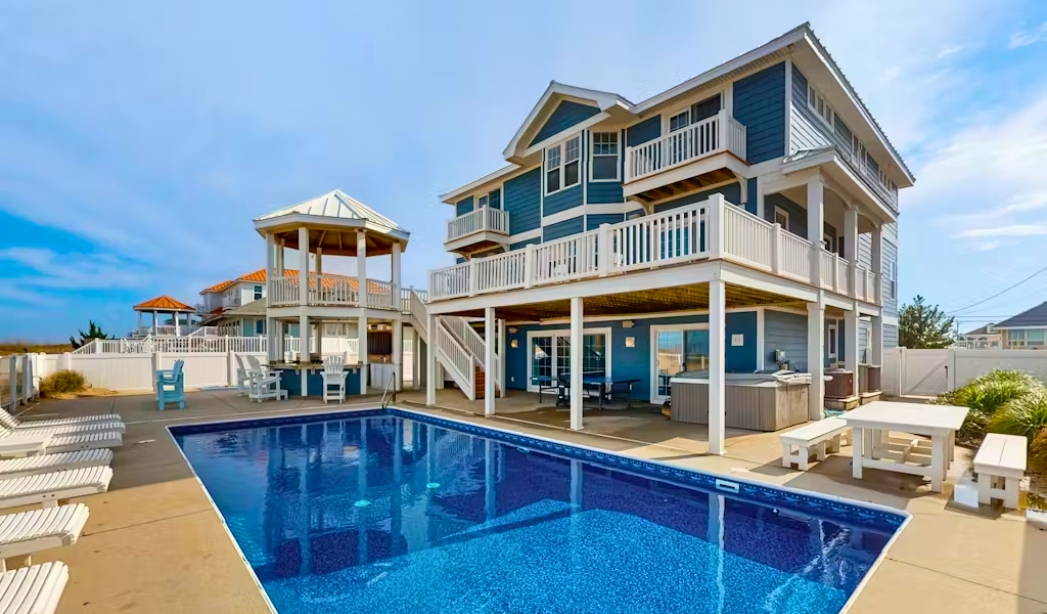 Exterior view of a blue house featuring a pool and deck, designed by Bay Colony Virginia Beach Home Builders