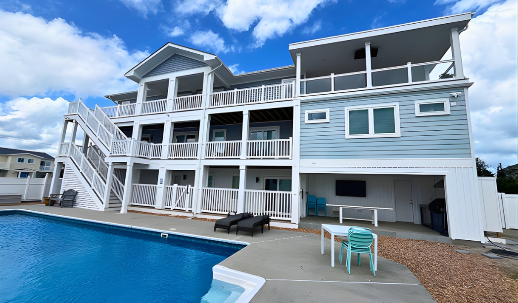 A large Virginia Beach house with a pool and stairs, showcasing the design by Bluefish Homebuilders in Bay Island.