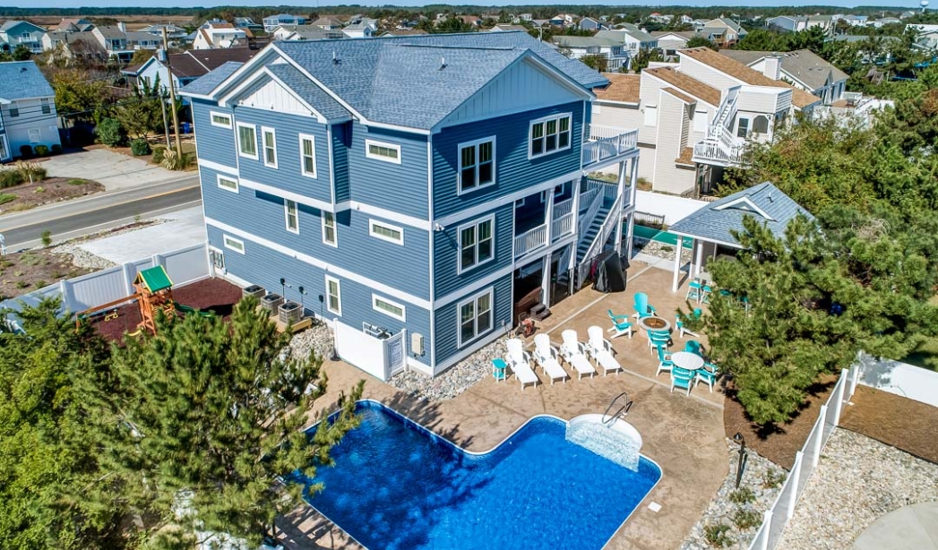 A blue house with a pool and deck, showcasing a Castleton Virginia Beach home by All-Sea-Suns builders.